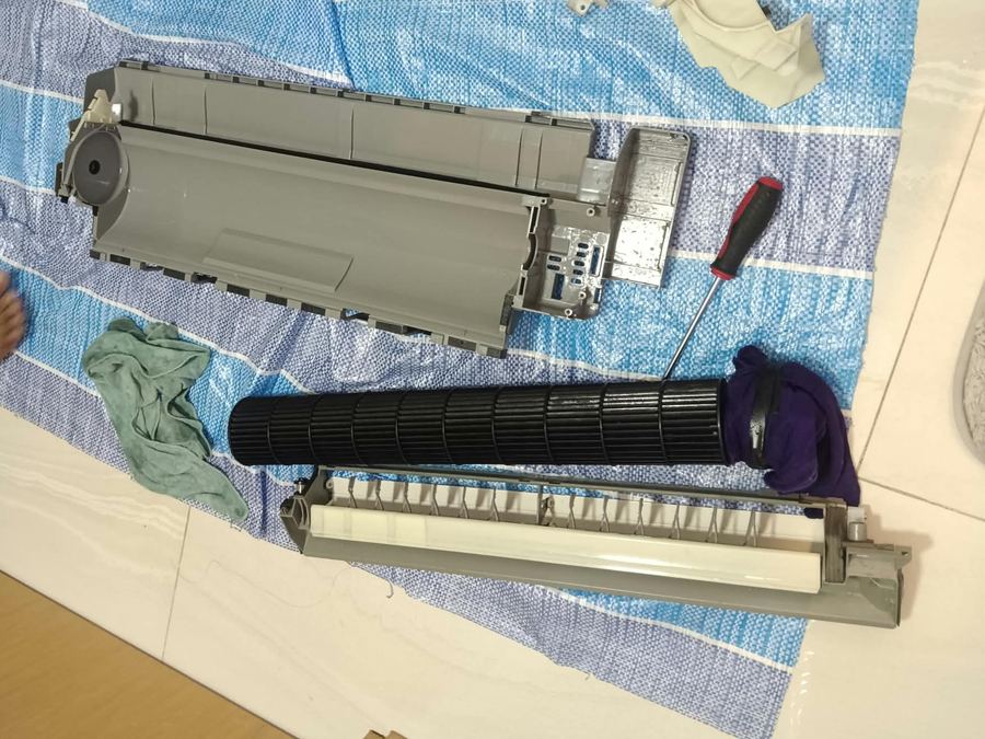 Aircon dismantled into parts on a protective sheet for a chemical overhaul