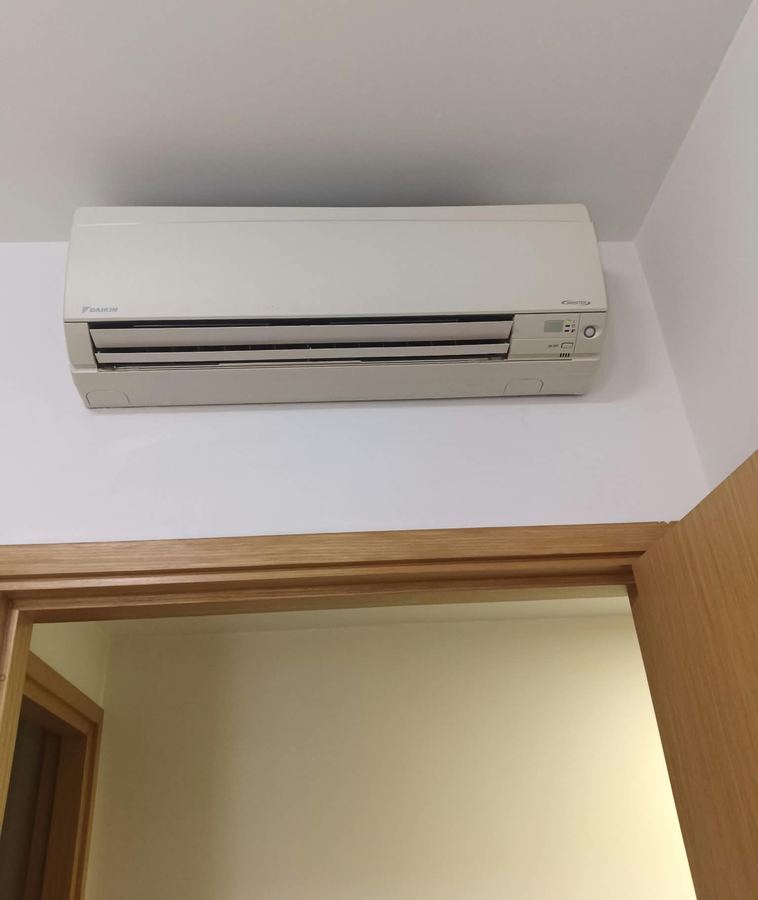 Wall-mounted aircon above a bedroom door after servicing
